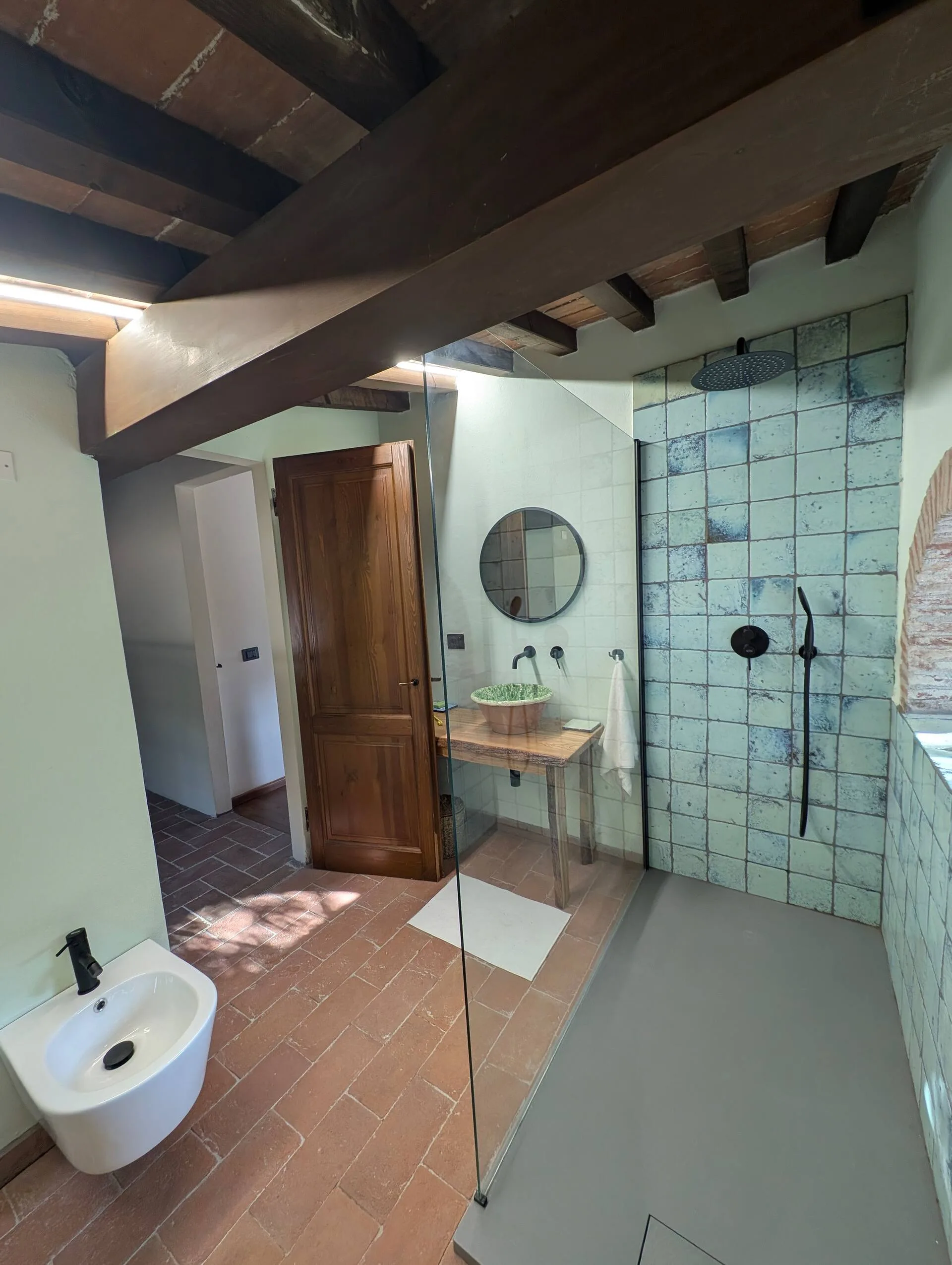Bathroom with green zellige tiles and a round arched window