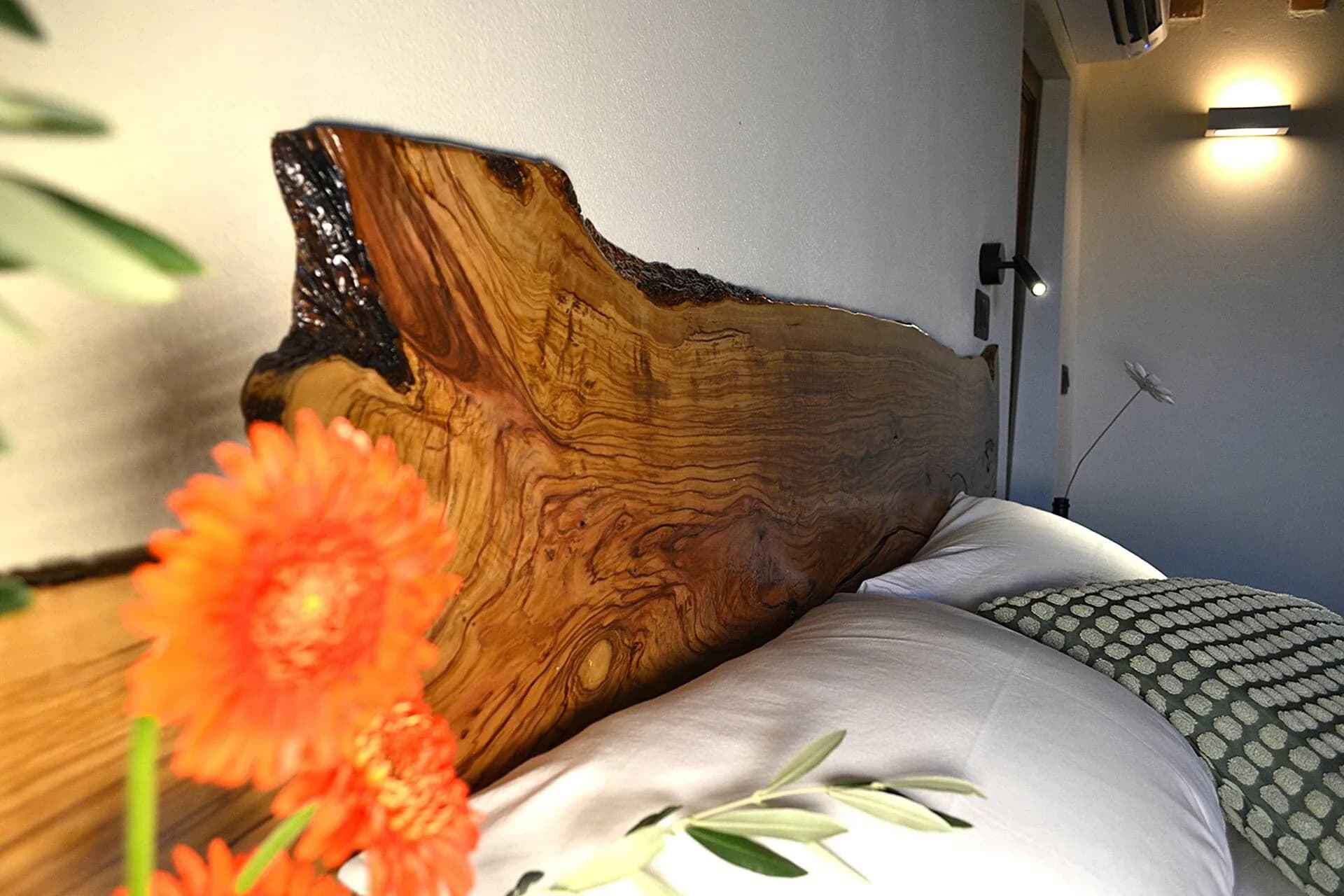 Live-edge wood headboard detail with a fresh flower
